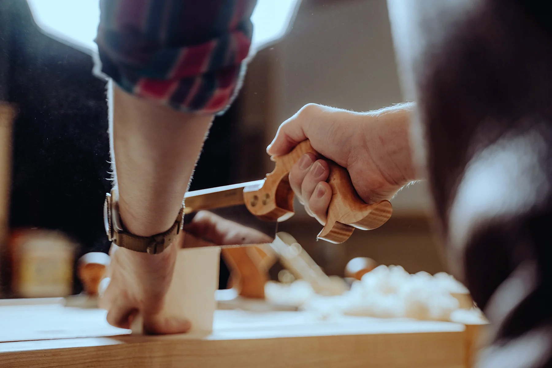 Mains sciant une pièce de bois maintenue sur un établi